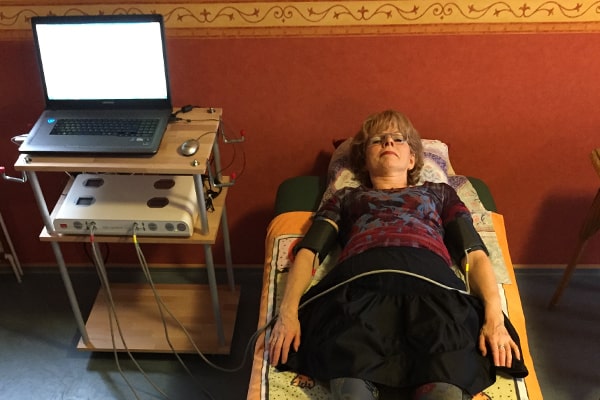 Frau liegt auf Behandlungsliege, angeschlossen an medizinisches Messgerät